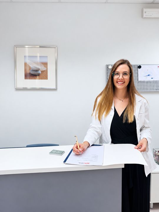 Professional d'ABC signant un document al taulell de recepció